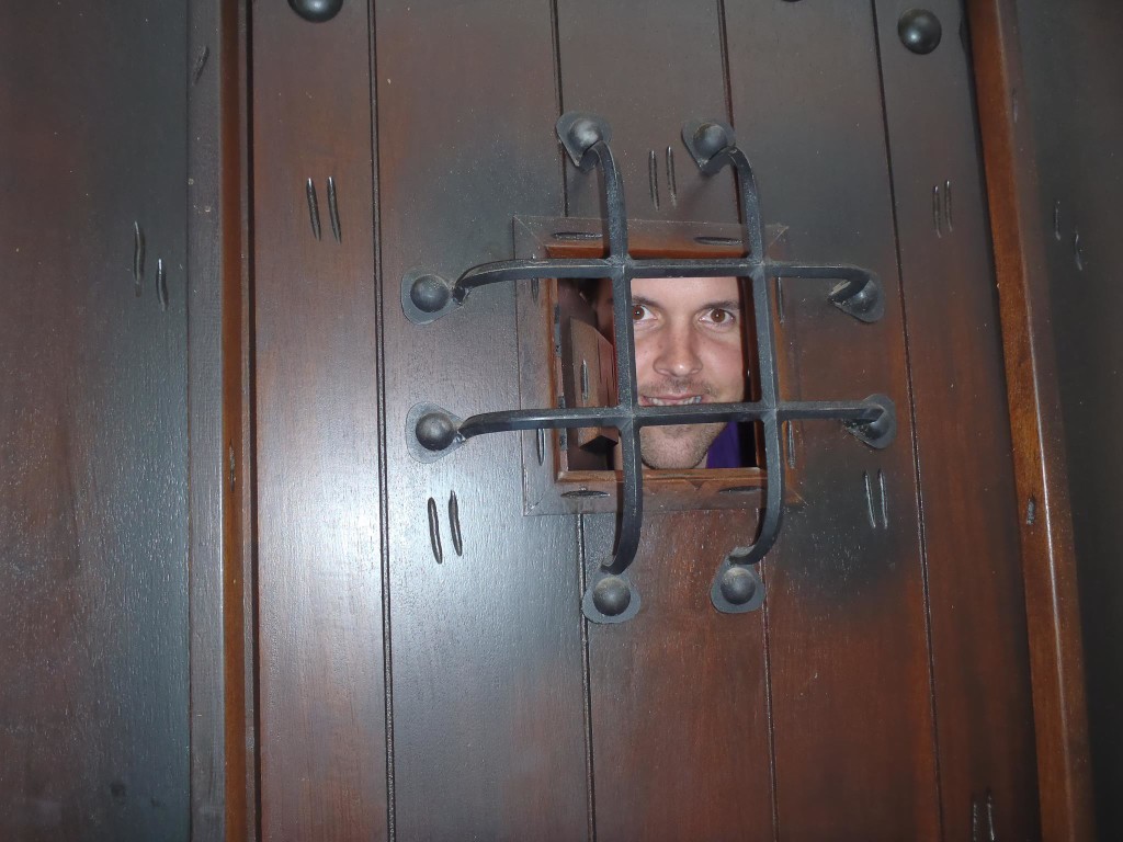 man peeps through huge wooden door with iron details