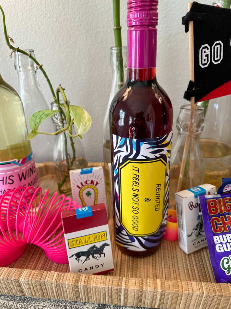 wine bottle with class reunion label (free printable) on tray with fake candy cigarettes and slinky at Murder High Reunion party