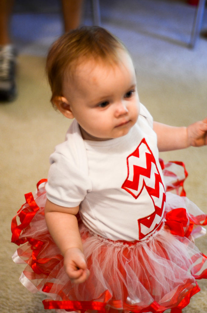 birthday girl wearing her 1st birthday outfit for a girl with a red and white tutu