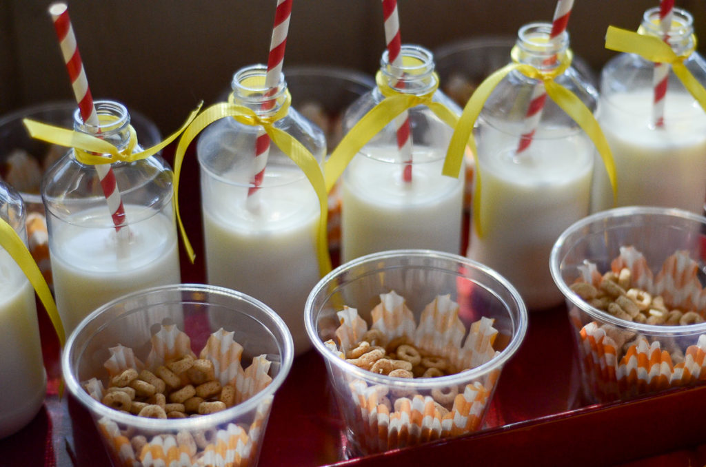 cups of Cheerios snacks with bottles of milk and striped straws