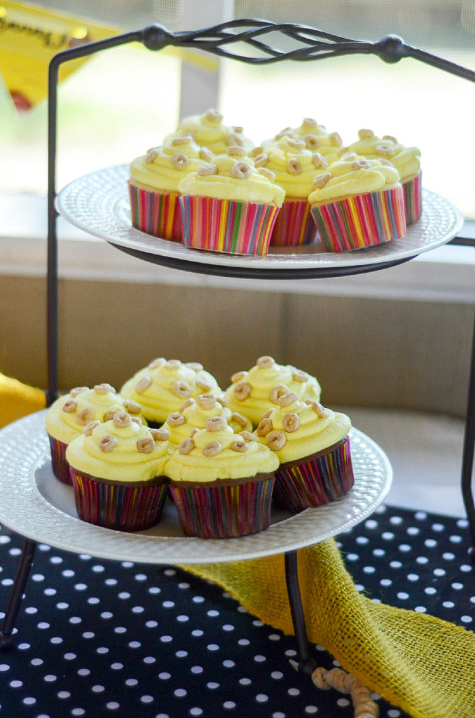 cupcakes with Cheerios for sprinkles on top of white plates in cake stand