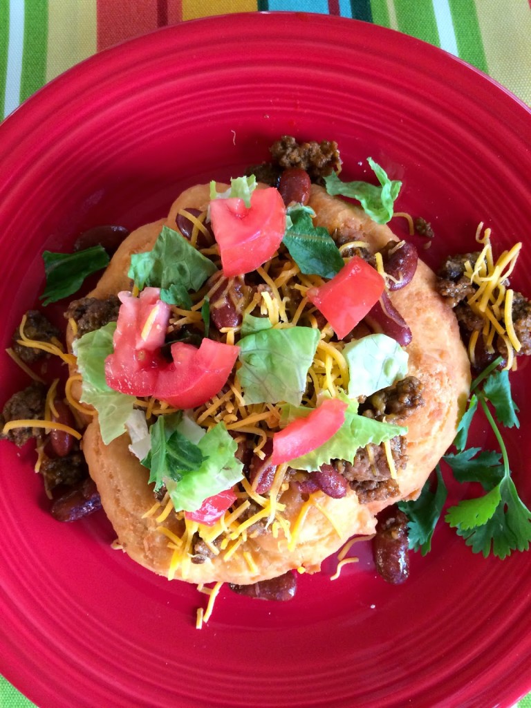 Indian Fry Bread Tacos on red plate with colorful table cloth 