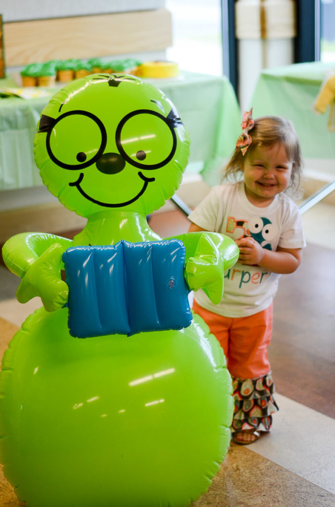 little girl poses with big green inflatable bookworm 