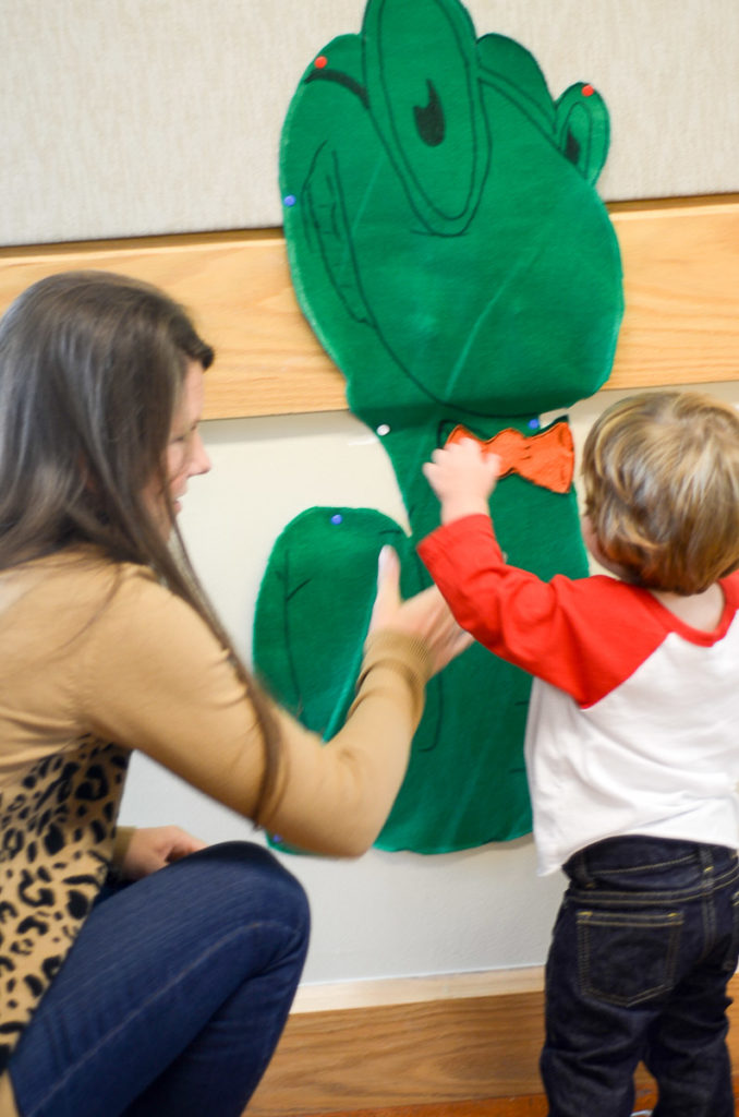 little boy plays pin the tail on the bookworm with his mom 