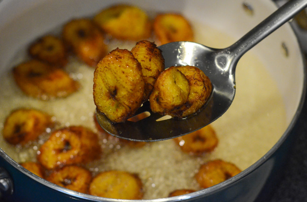 someone removes platanos maduros from hot skillet to napkin-covered plate