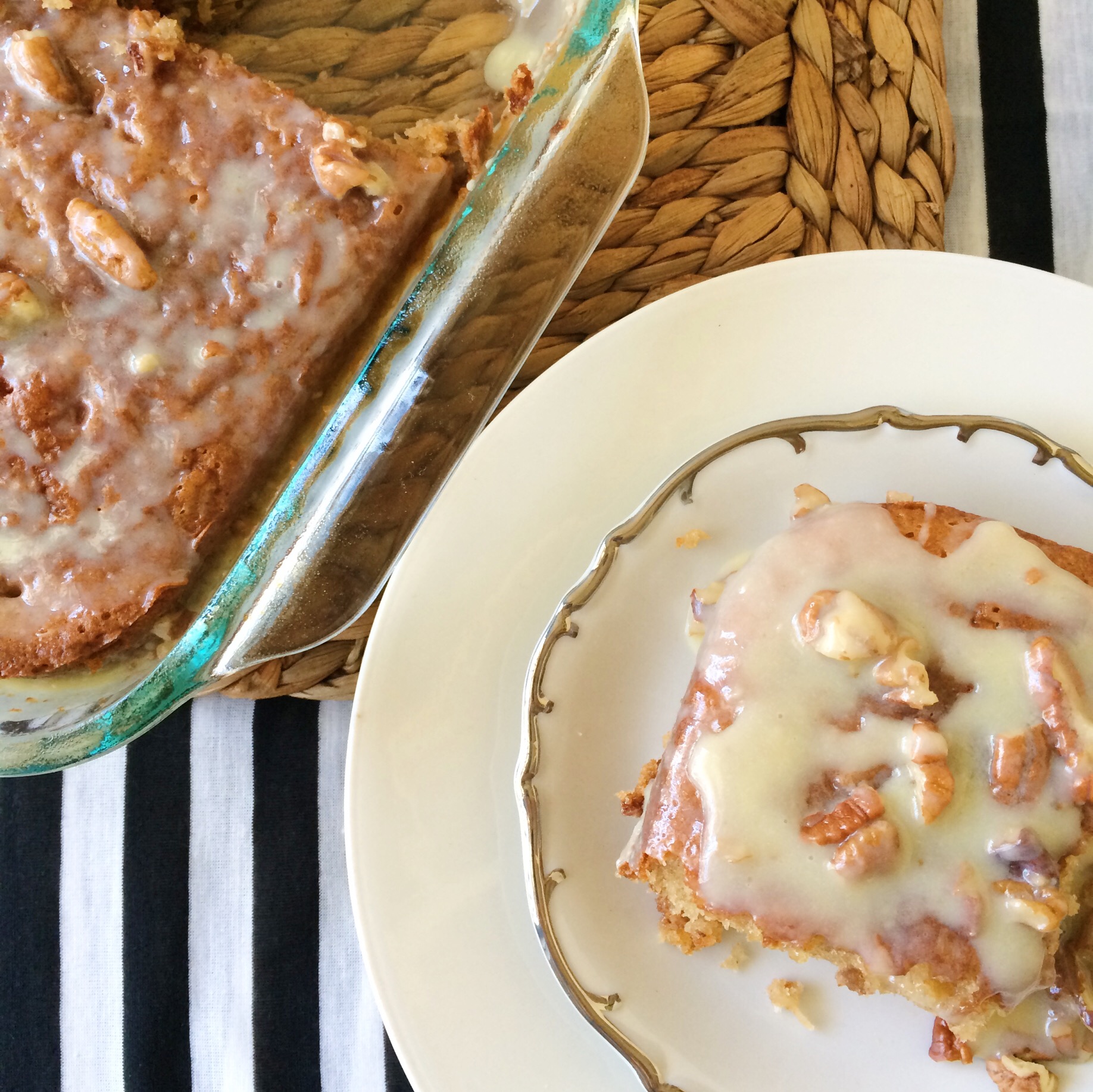 butter pecan praline poke cake slice on white china with cake pan at back