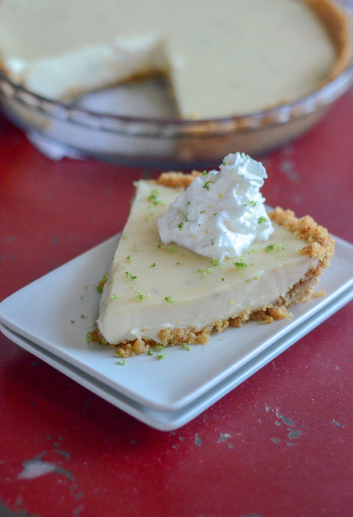 slice of Key West key lime pie on white plate with pie in background 