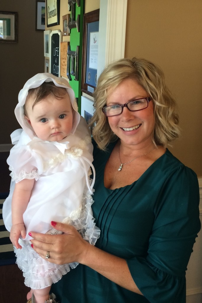 baby in custom christening gown from wedding gown held by her godmother after her baptism