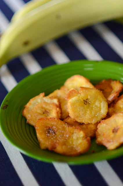 platanos fritos - fried green plantains - on a greet plate with a navy blue striped cloth