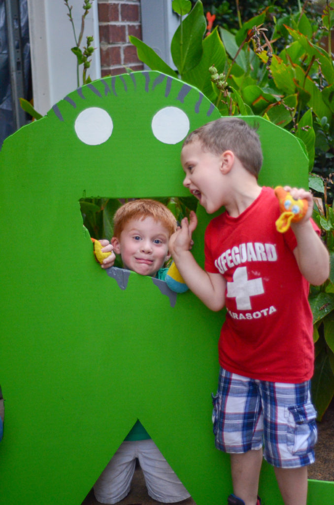 boys pose with wooden monster bean bag toss game at little monster birthday party