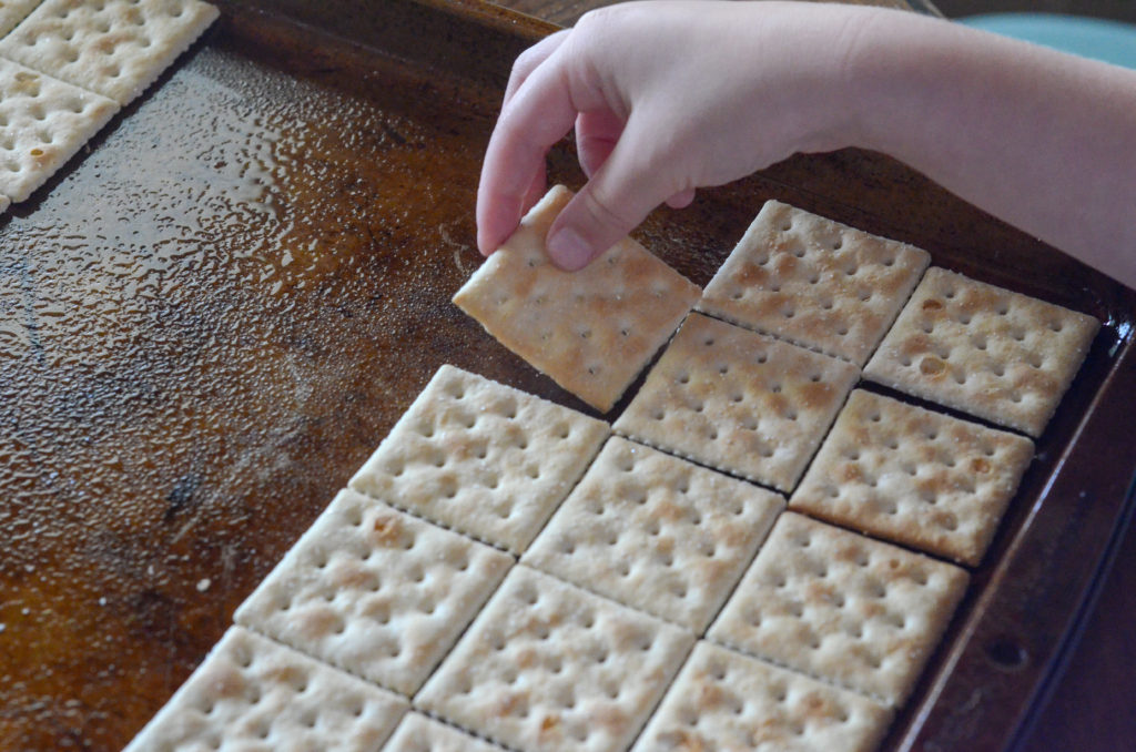 little girl puts crackers on baking sheet