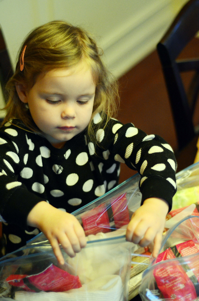 little girl in polka dot shirt packs hygiene kits for homeless residents 