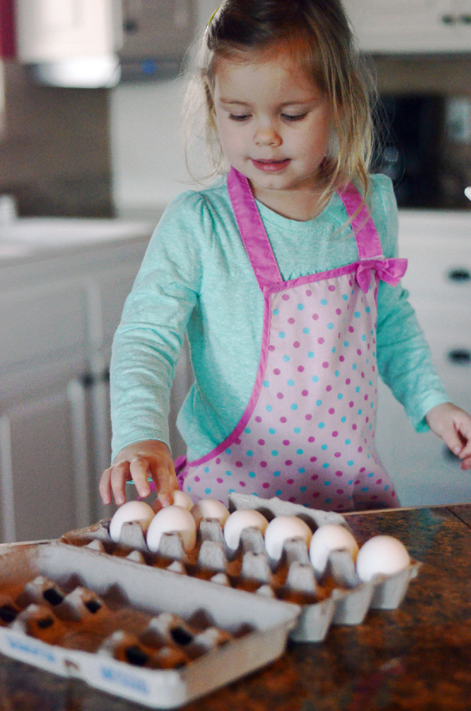 little girl choosing an egg from an egg carton 