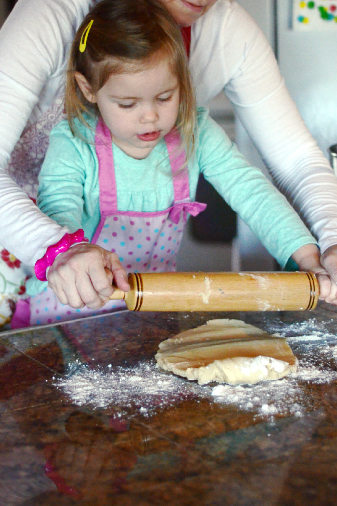 mom and toddler daughter rolling dough