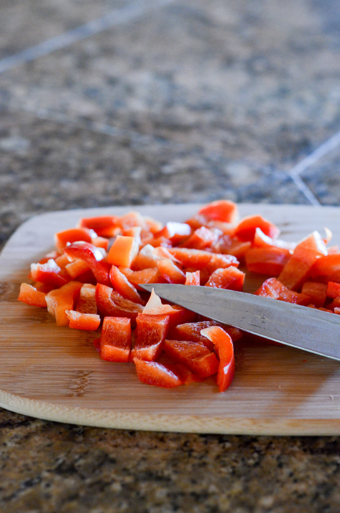 chopped red bell peppers on cutting board with knife
