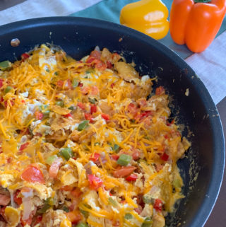 migas on huevos Tex Mex egg scramble in black skillet with bell peppers in back