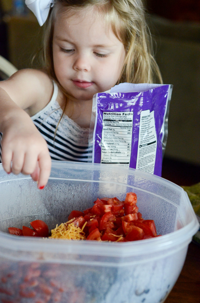 little girl helping prepare a salad 