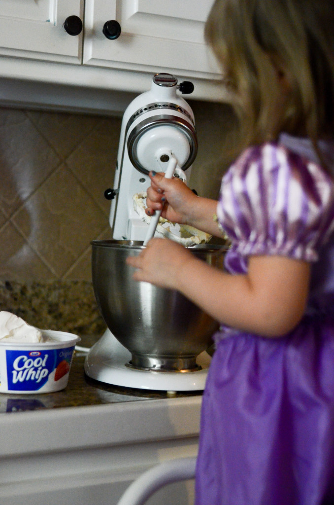 little girl makes cream cheese layer for strawberry pretzel salad