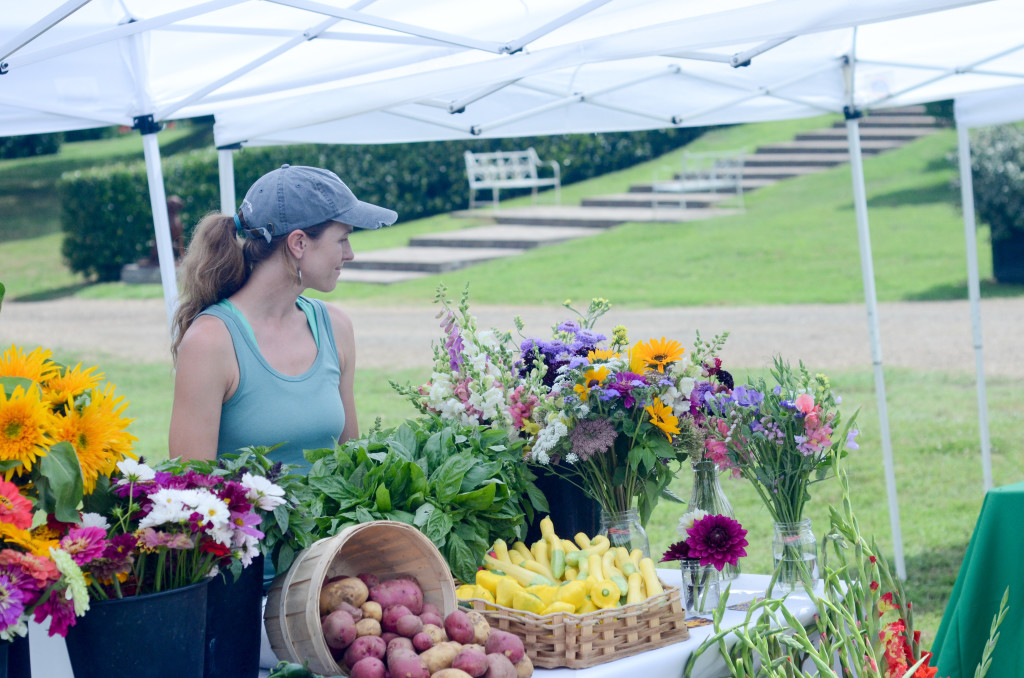 a woman sells flowers and veggies at the farmers' market - The Gifted Gabber