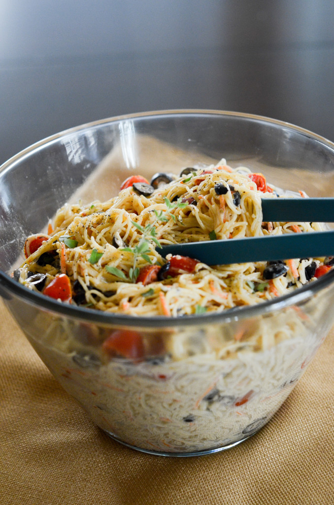 tongs grabbing cold angel hair pasta salad with Italian dressing