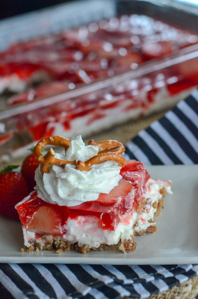 strawberry pretzel salad on white plate with dish in back