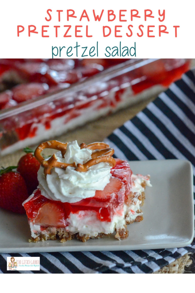 plate of strawberry pretzel salad in front of baking dish on striped textiles