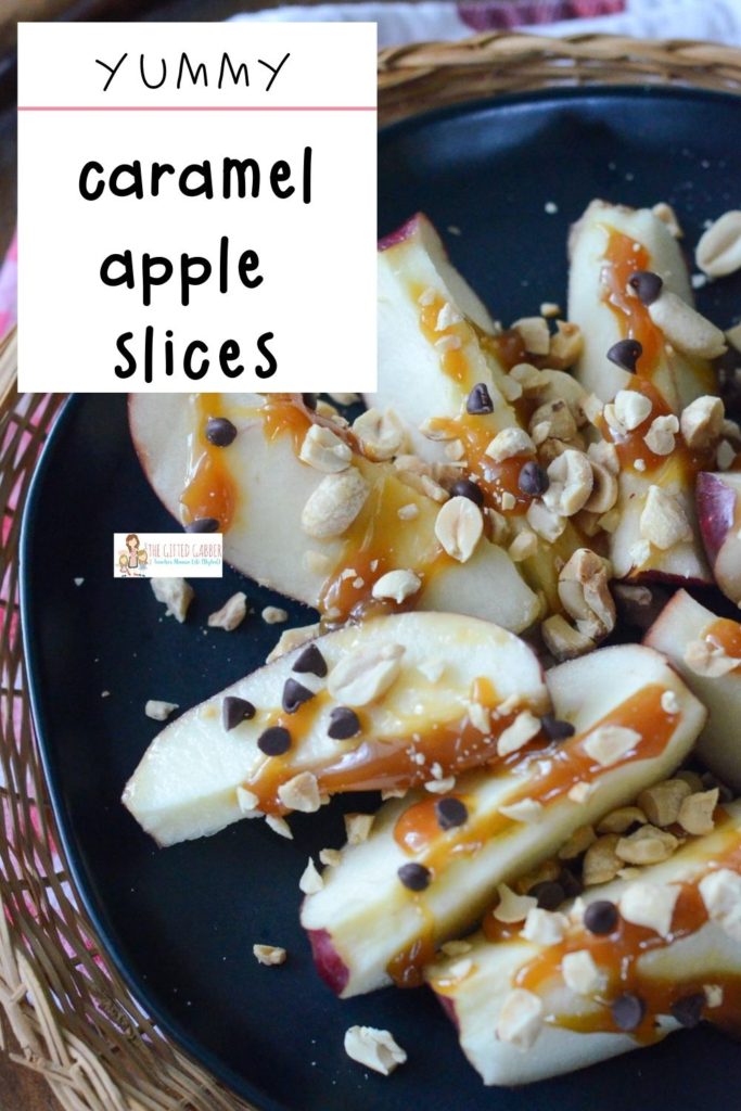 apple slices with caramel, peanuts and chocolate chips on black platter