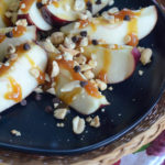 caramel apple slices on black plate on wicker charger