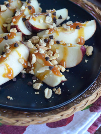 caramel apple slices on black plate on wicker charger