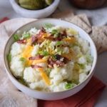 loaded baked potato dip in white bowl with tortillas