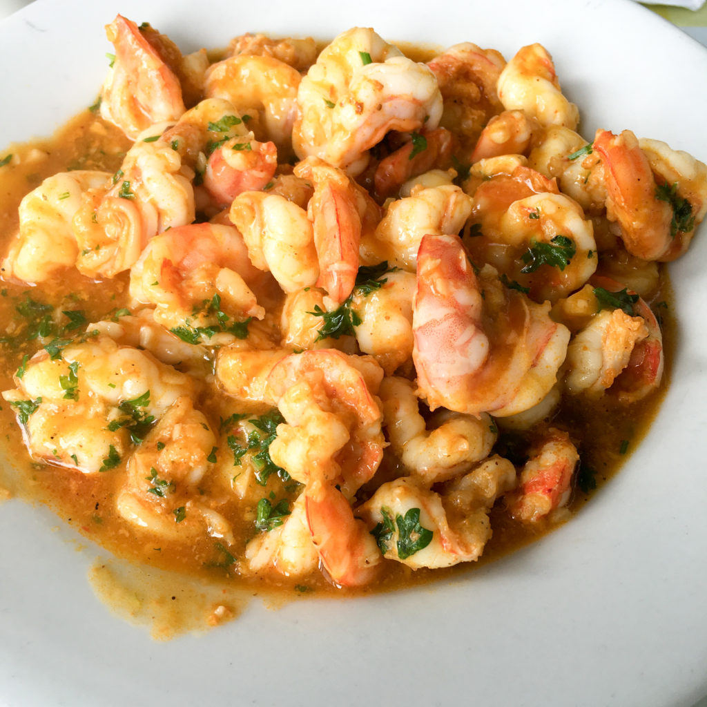 a white bowl of shrimp in sauce 
