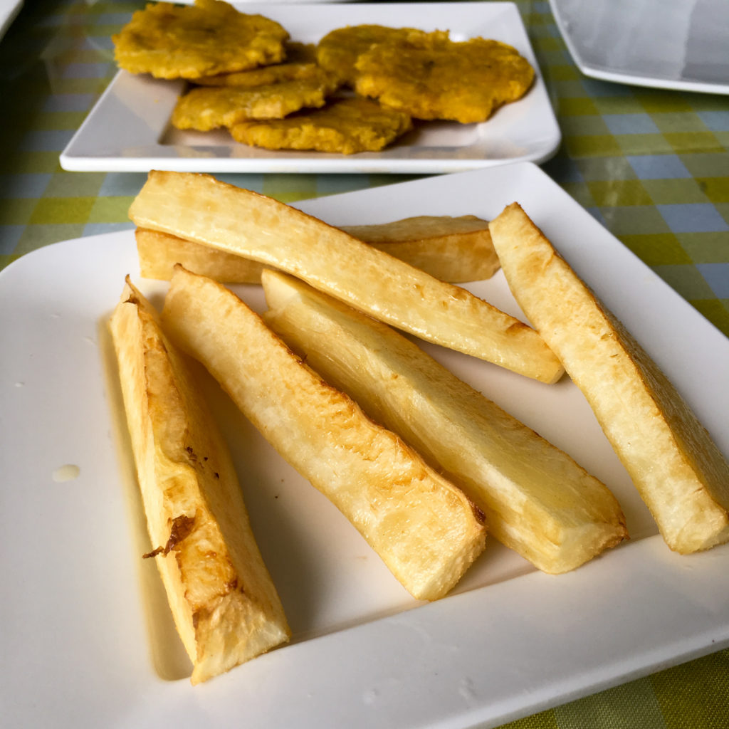 fried yuca and patacones on white plates 