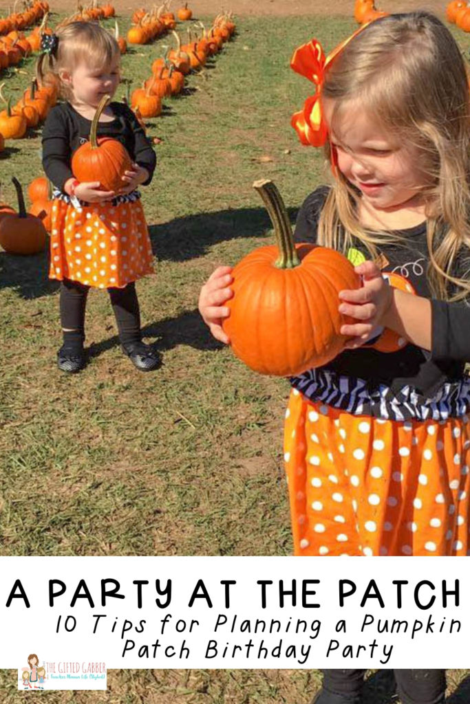 two little girls holding pumpkins at a pumpkin patch birthday party