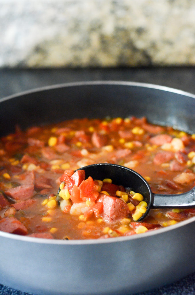 spicy shrimp and corn soup in skillet with black serving spoon 