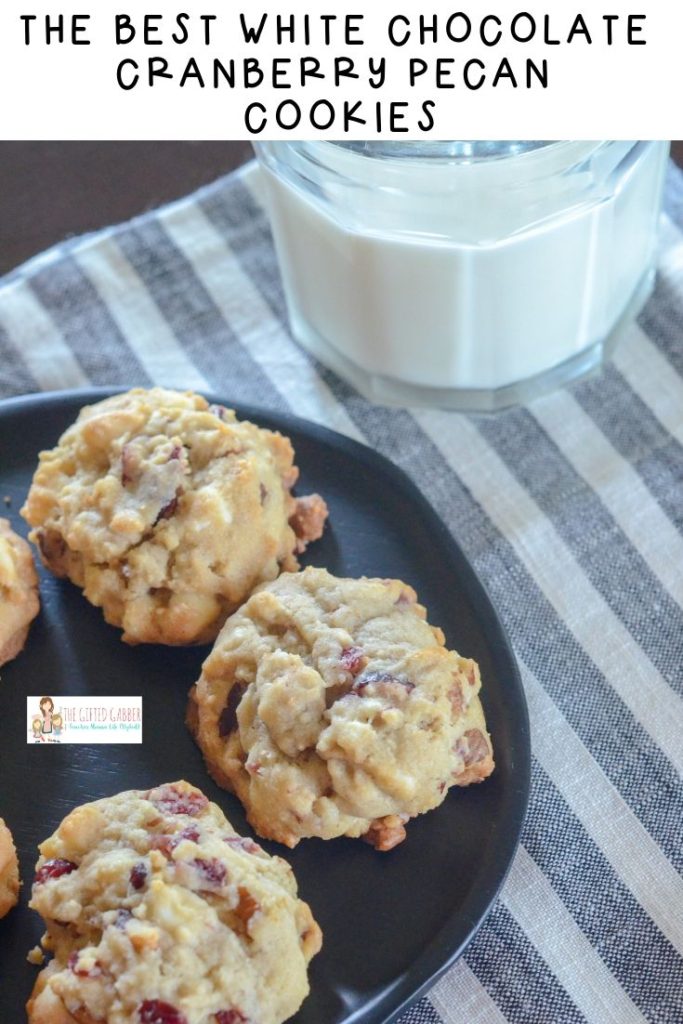 cranberry cookies on black plate with glass of milk on striped tablecloth