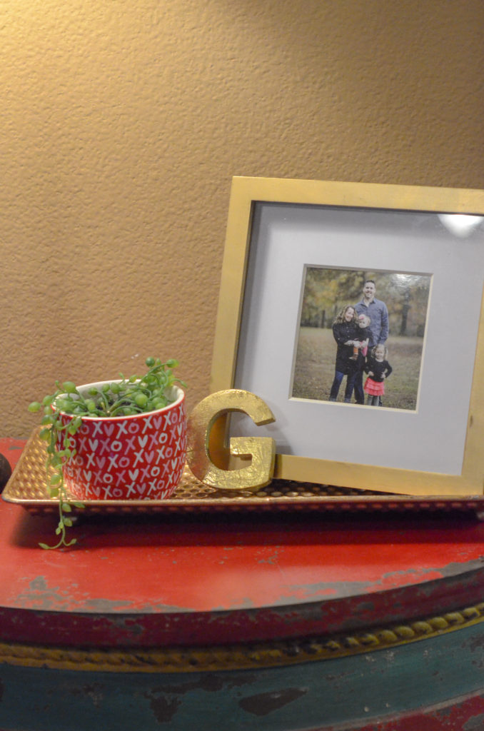 a String of Pearls plant rests inside an XOXO bowl with a family photo in a frame