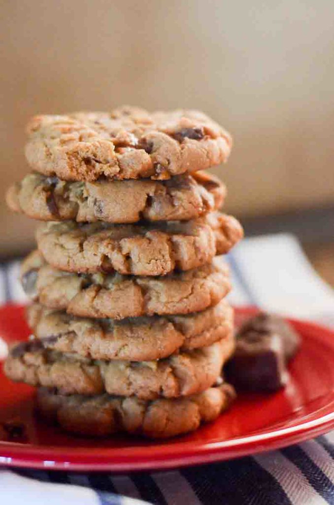 tall stack of peanut butter cookies on a plate with Snickers bites