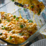 sour cream chicken enchilada with green chilies being lifted out of glass pan