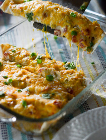 sour cream chicken enchilada with green chilies being lifted out of glass pan