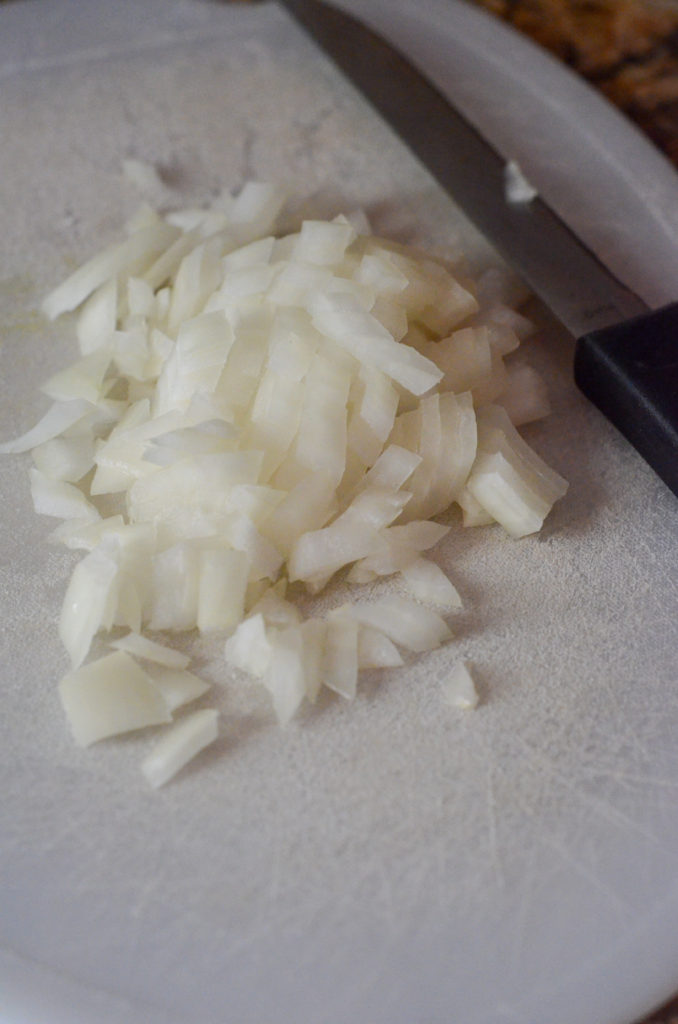 chopped onions and knife on white cutting board