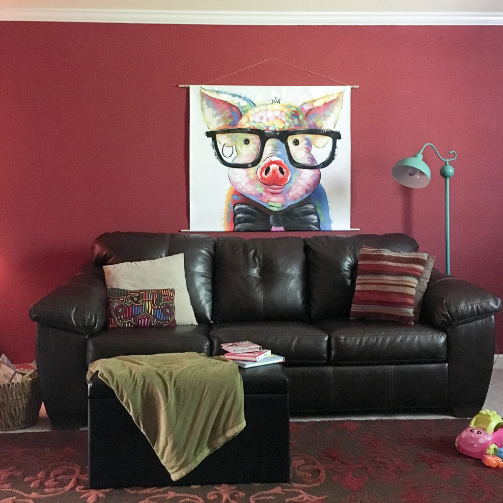 a brown sofa on red rug with a large unframed canvas displayed on wall above