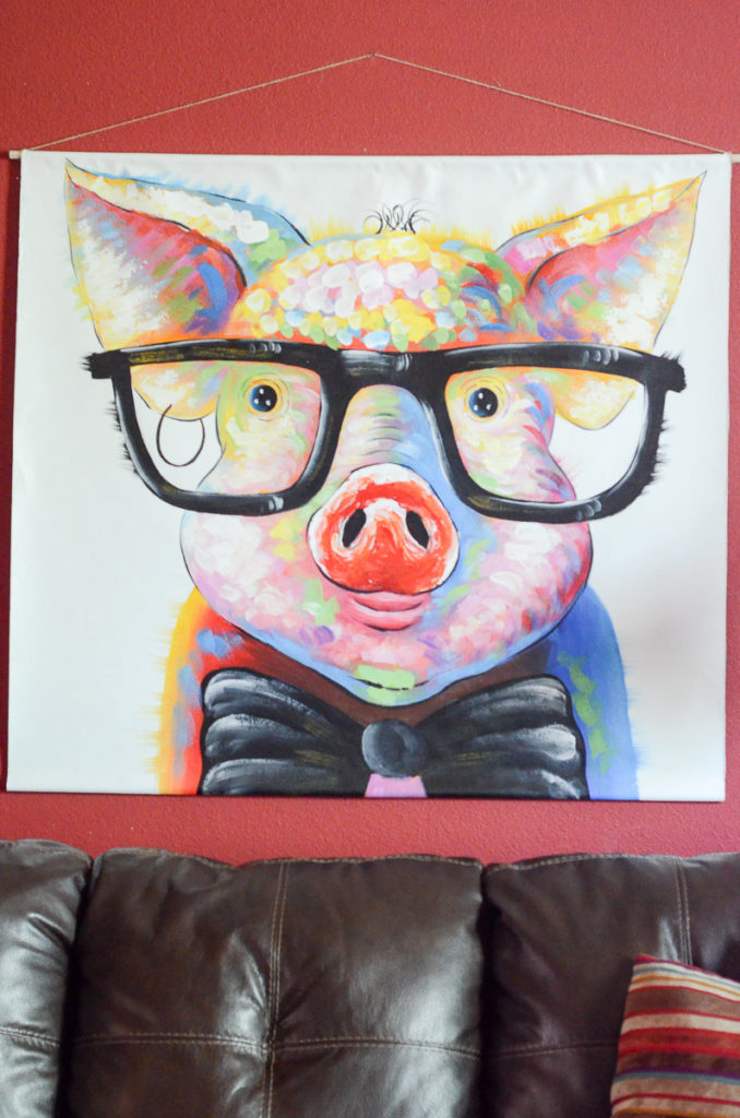large pigs wall art hangs on red wall above brown sofa as an idea for how to hang a canvas print unframed 