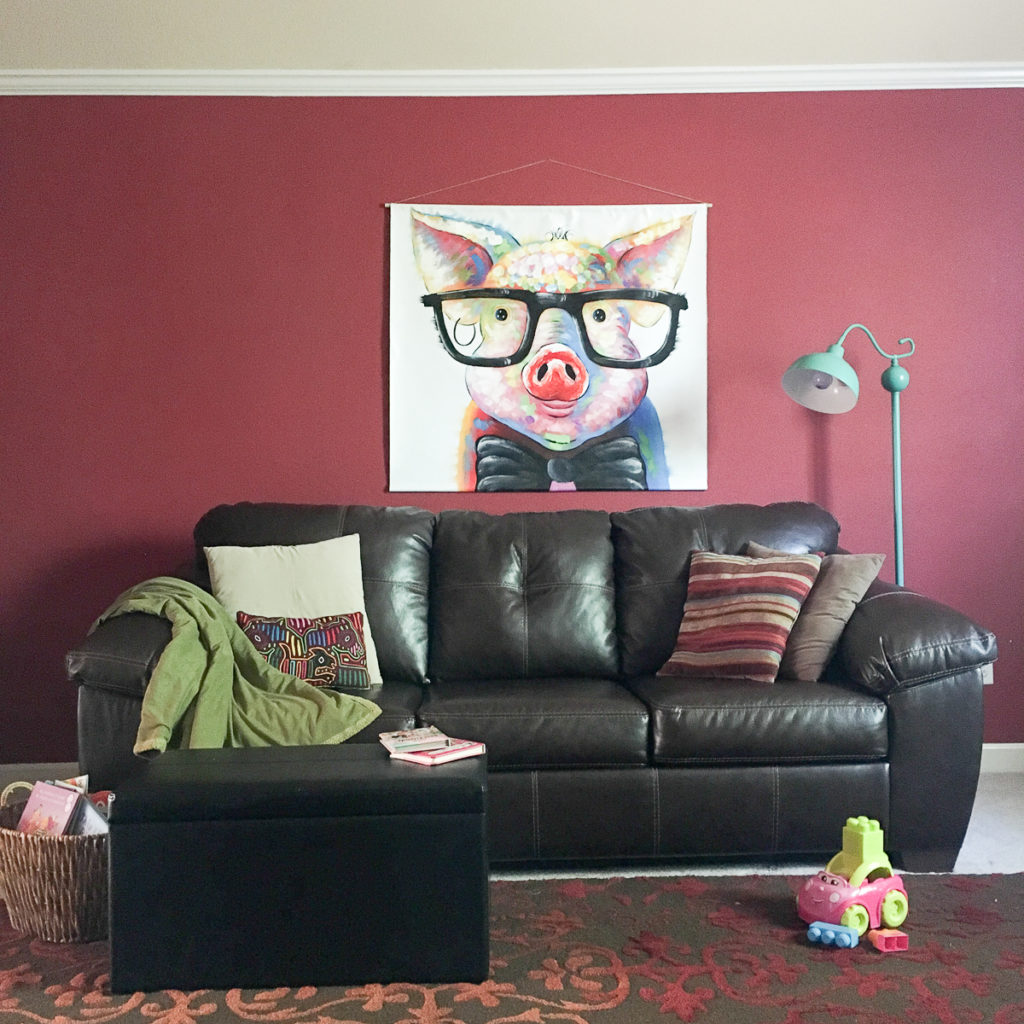 large quirky animal wall art hangs above brown couch as idea for how to hang a canvas print on rope