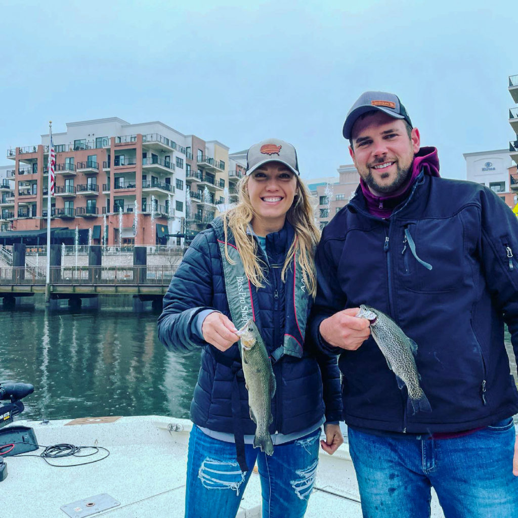 couple shows trout fish they caught while trout fishing on Lake Taneycomo with OutCast Adventures