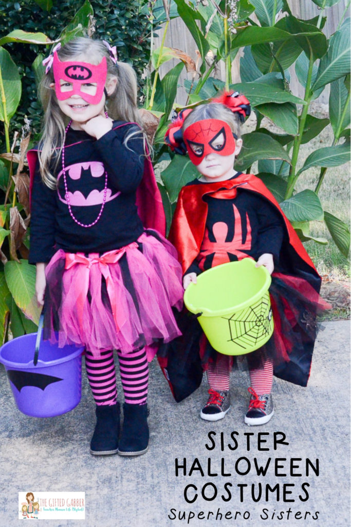 Superhero sisters holding candy buckets for Halloween with text overlay