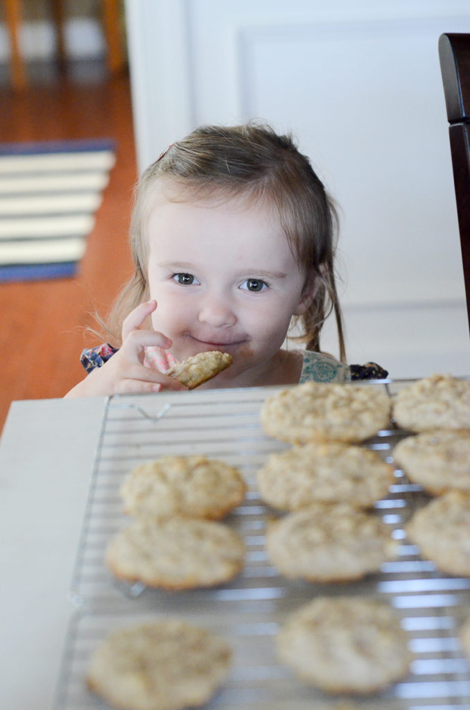 little girl grins over tray of cookies 