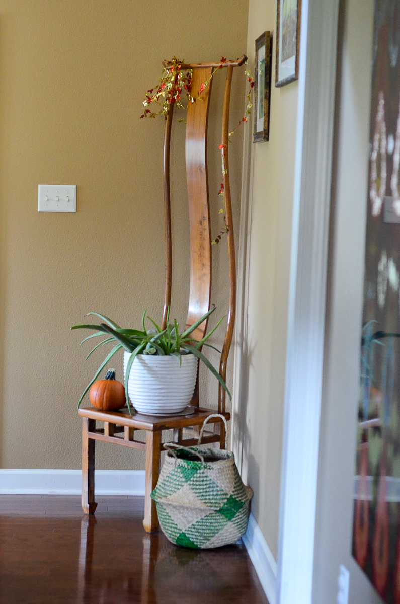 tall chair in home entry with a pumpkin and a plant