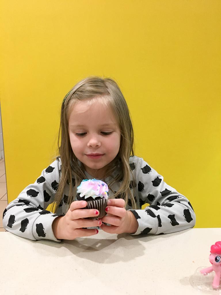 girl eats a cupcake while at a small McDonald's party for her birthday 