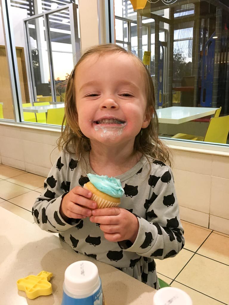 little girl eats a cupcake at a family McDonald's birthday party for kids 