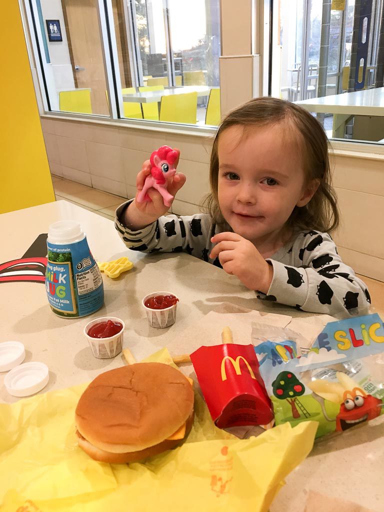 little girl shows her Happy Meal toy while eating at a McDonald's birthday party for kids 